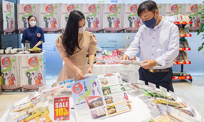 ホーチミン市1区の日本製品専門モールで、お客さんに日本の即席めんを紹介するホクセイシャベトナムの社長(右) ⓒ VnExpress ホーチミン市1区の日本製品専門モールで、お客さんに日本の即席めんを紹介するホクセイシャベトナムの社長(右) ⓒ VnExpress